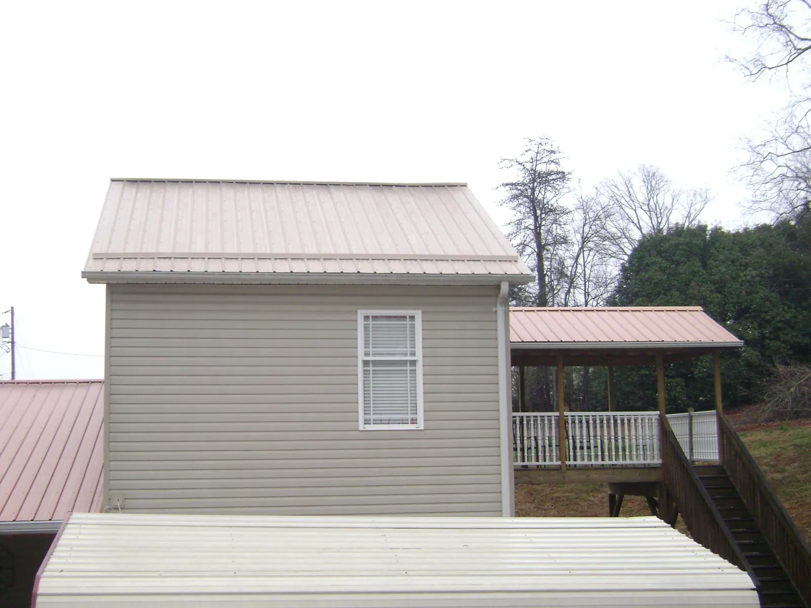 Tan metal roofs on a two story addition and attached porch, from a Roof Replacement job in Bridgeville