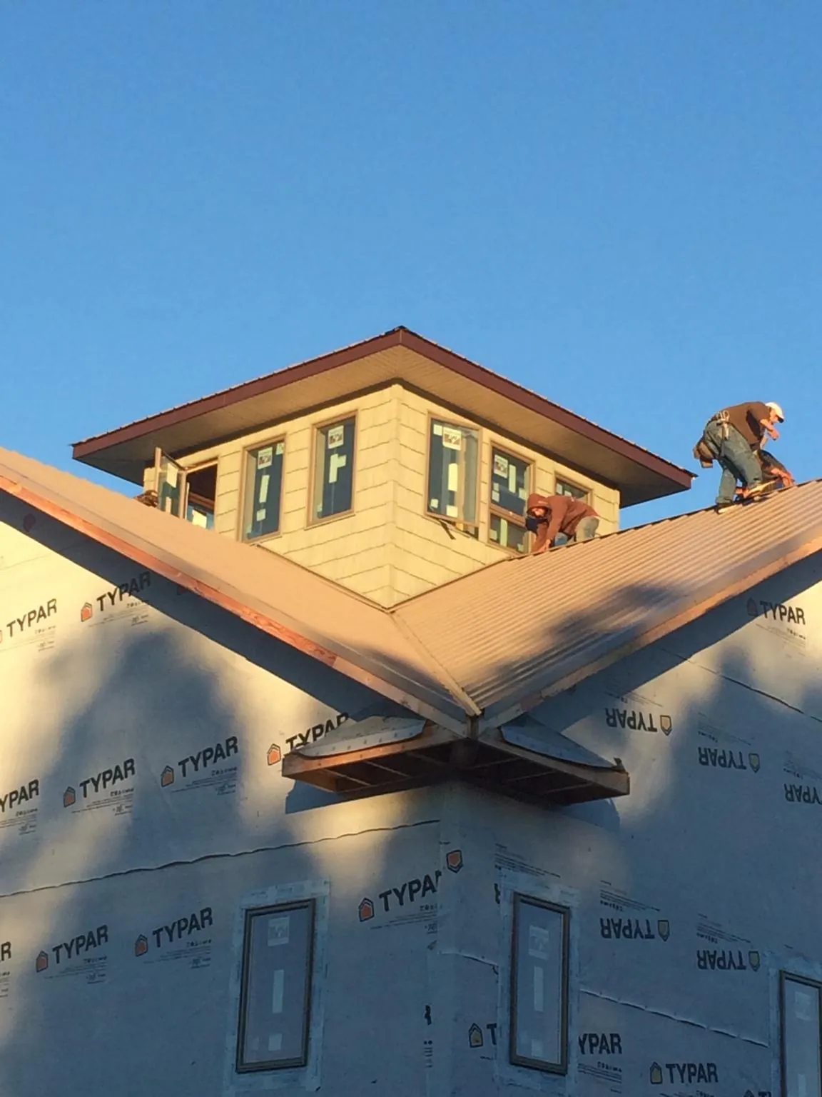 Roofers working around a rooftop cupola on a new metal roof at sunset — Roof Waterproofing in Bridgeville by Roofing Brothers
